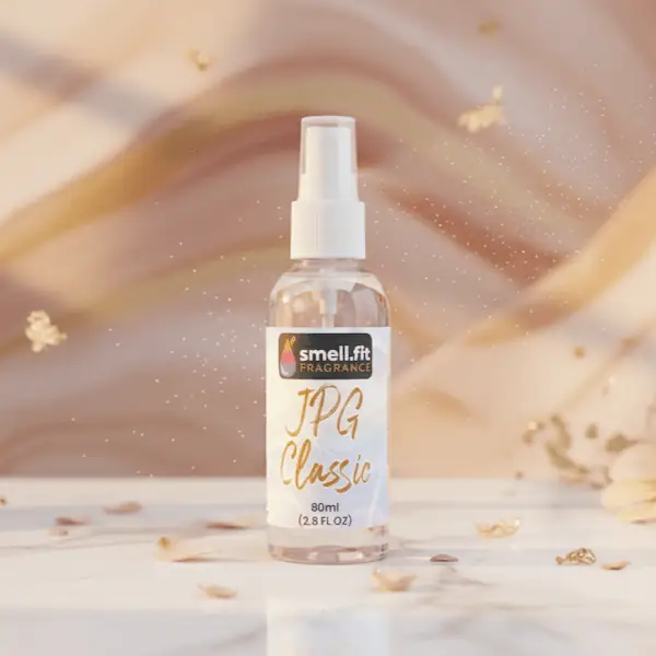Product image of Smell.fit Fragrance 'JPG Classic' 80ml (2.8 FL OZ) mist spray bottle. The bottle is set on a white marble surface scattered with gold flakes and light pink flower petals, against a luxurious, shimmering golden and peach-colored fabric background.
