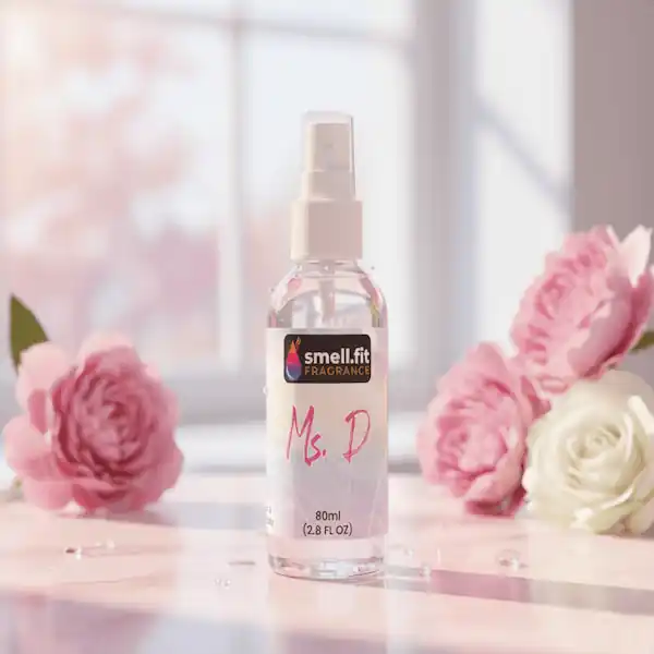 Product image of Smell.fit Fragrance 'Ms. D' 80ml (2.8 FL OZ) mist spray bottle. The bottle is set on a light pink marble surface with water droplets, surrounded by large, soft-focus pink and white rose or peony flowers, in a bright, sunlit window setting.